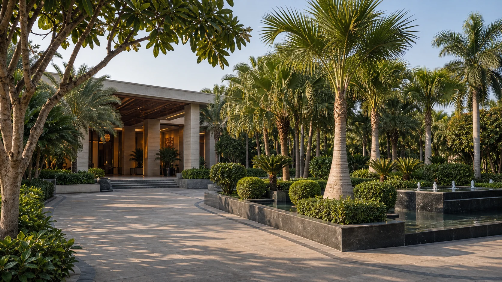 Luxury hotel arrival court landscape with palms, water feature, clipped planting, and polished guest circulation.