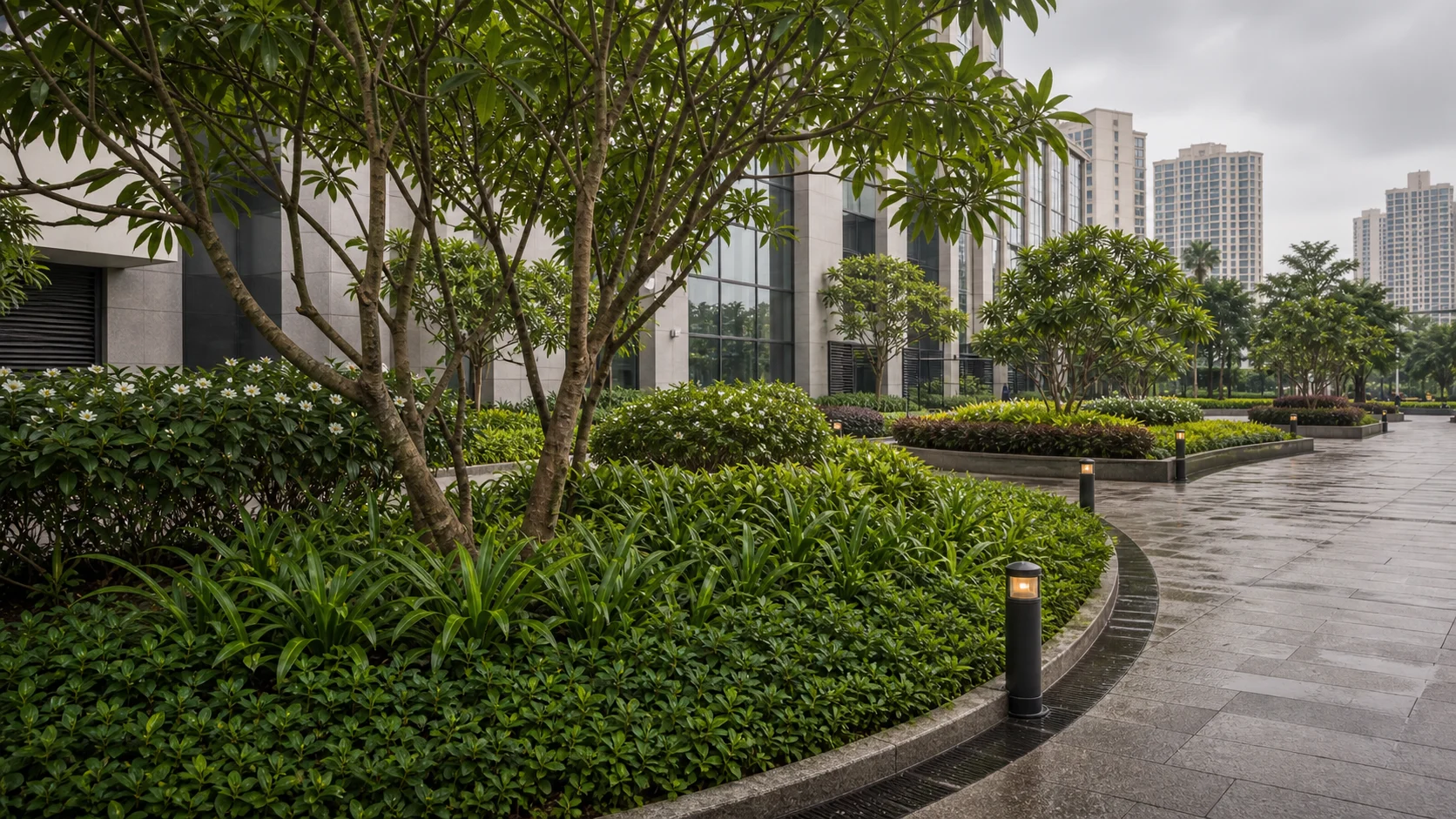 Mumbai commercial landscape with monsoon-wet paving and coastal-tolerant planting on a podium arrival.