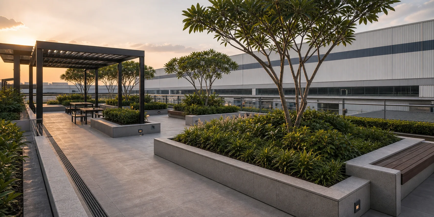 Drip emitter grid in commercial softscape bed with steel edging, layered shrubs, and groundcover on a podium.