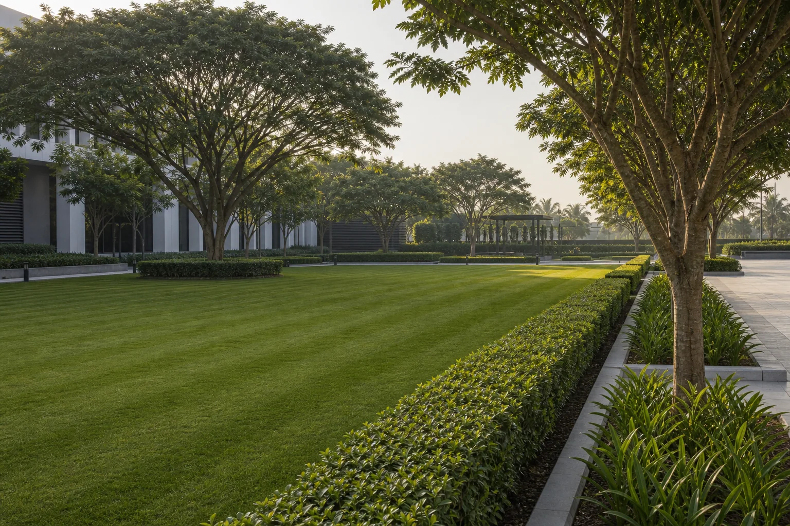 Commercial campus lawn mowing and hedge maintenance along a pedestrian walkway.