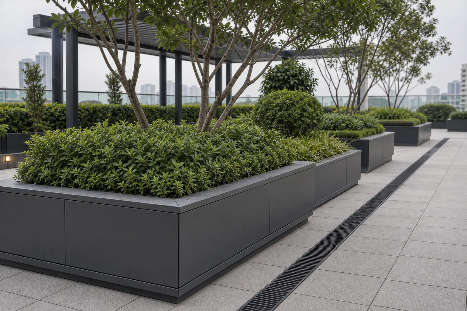 Podium garden paving beside raised planters with drainage-led detailing for commercial amenity space.