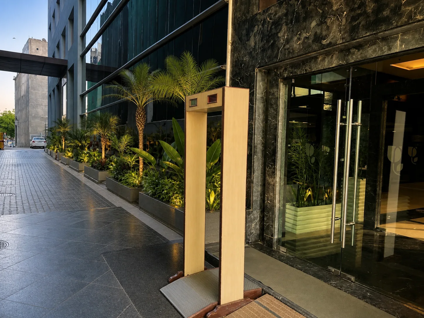 Country Inn Gurugram side entrance with a clean paved approach, palms and layered planting beside the glazed hotel facade.