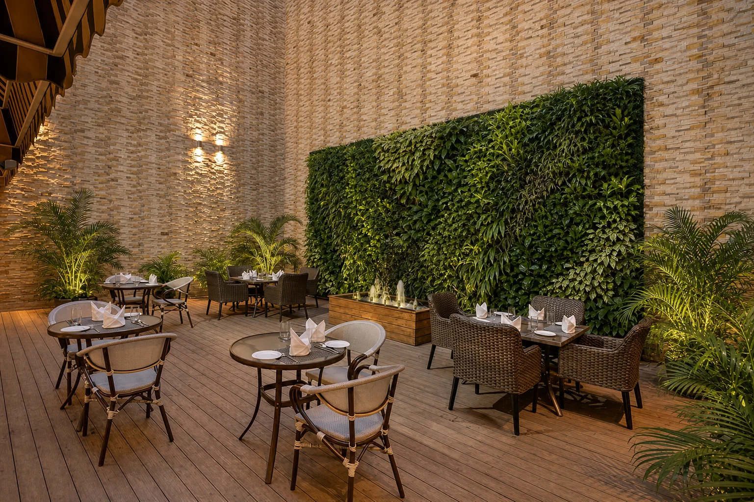 Country Inn & Suites Zirakpur outdoor dining courtyard with a dense planted wall, cascading water, timber decking and palms.