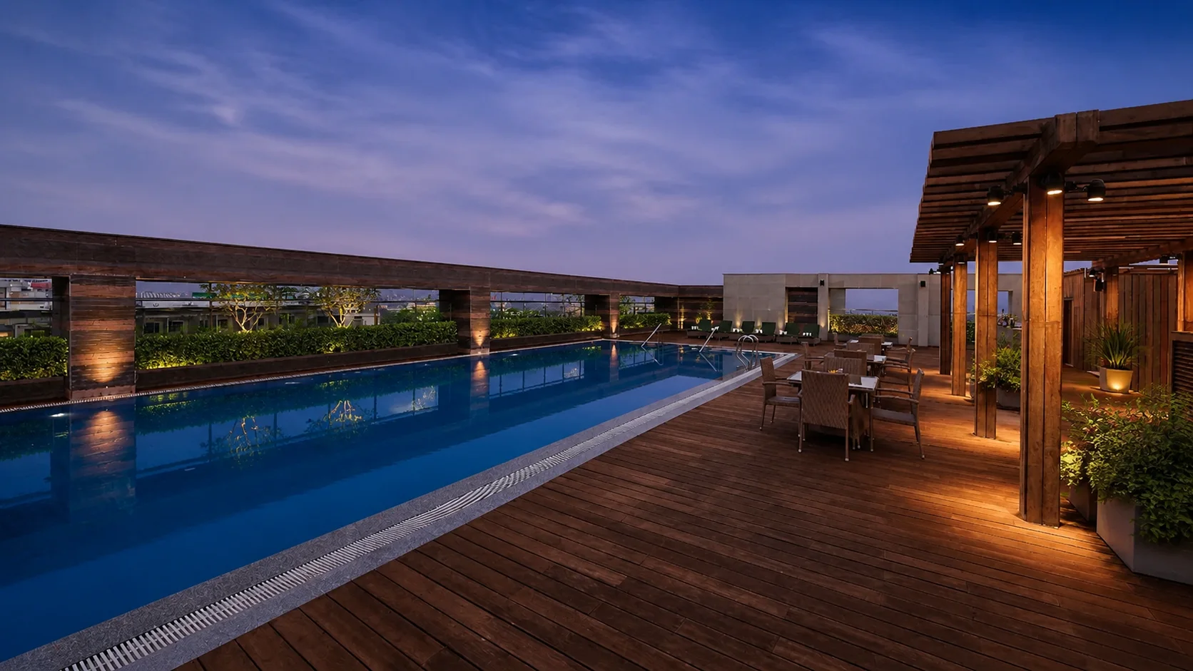 Holiday Inn Jaipur rooftop pool at blue hour with clear water, timber decking and tropical planting