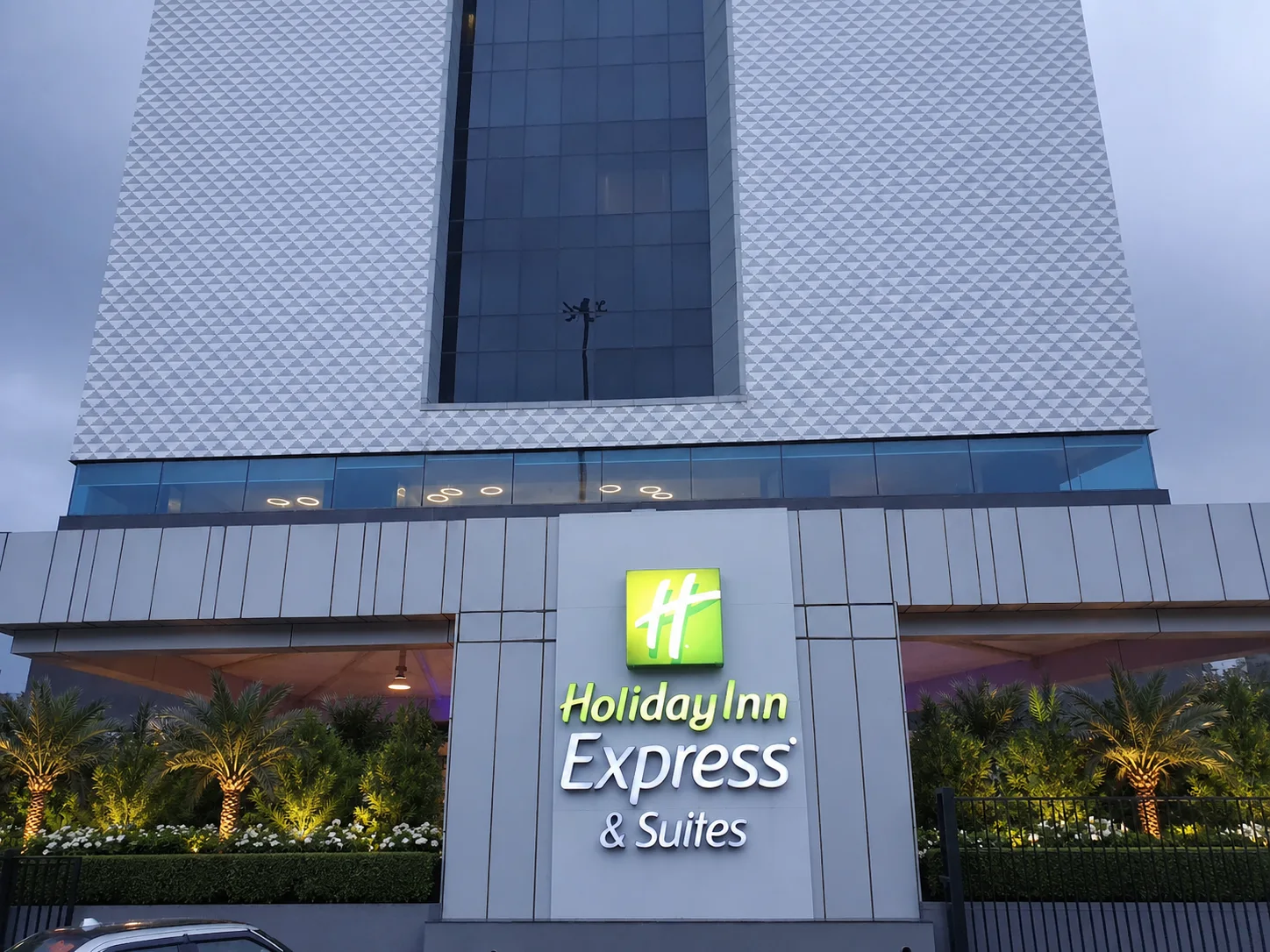 Holiday Inn Express & Suites Jaipur identity sign with structured palms, clipped hedges and warm landscape lighting.