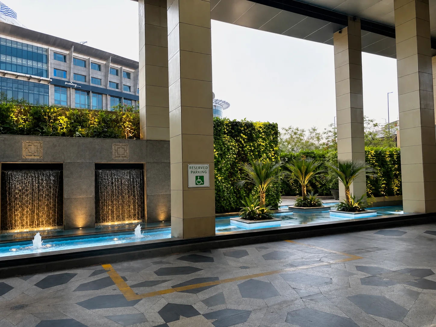 Holiday Inn Jaipur entrance water court with active fountains, sculptural palms and dense planted walls.
