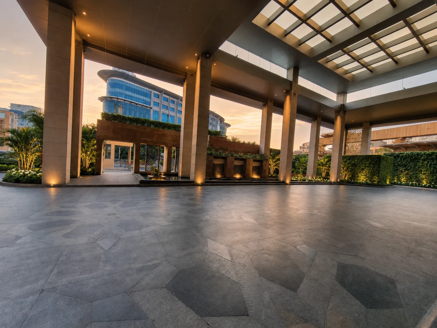 Holiday Inn Jaipur covered arrival with clean paving, illuminated columns, fountains and planted walls.