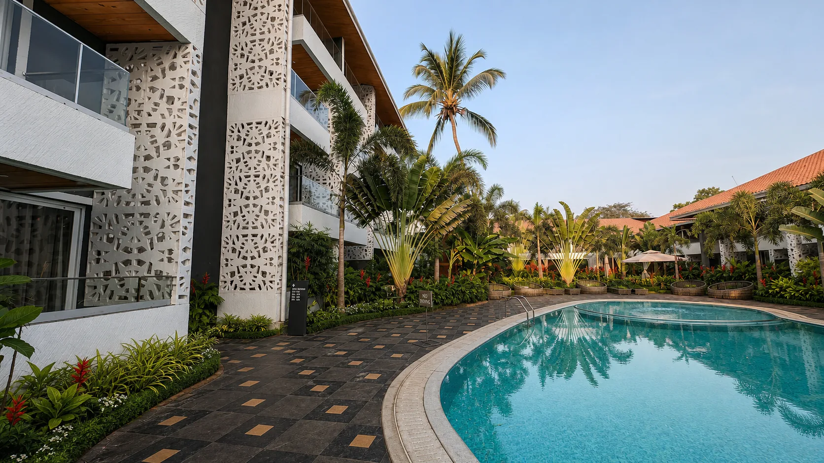 Hyatt Place Goa Candolim pool courtyard with clear water, mature palms and layered tropical landscaping