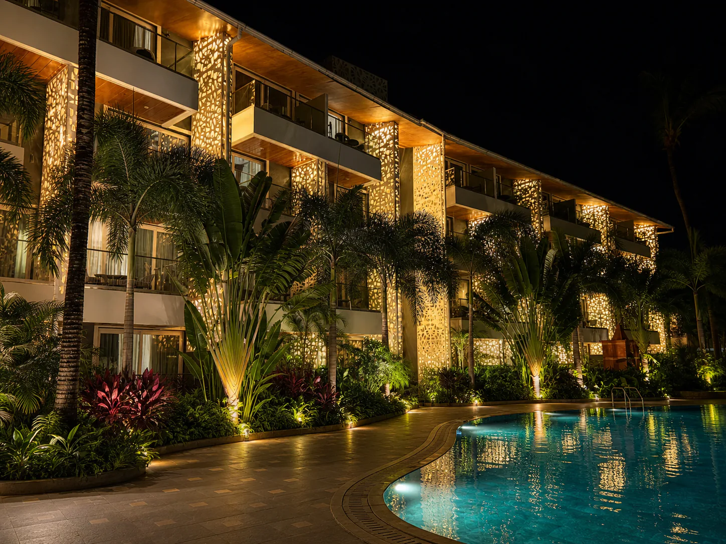 Hyatt Place Goa Candolim illuminated night pool and guest-room facade reflected in clear water