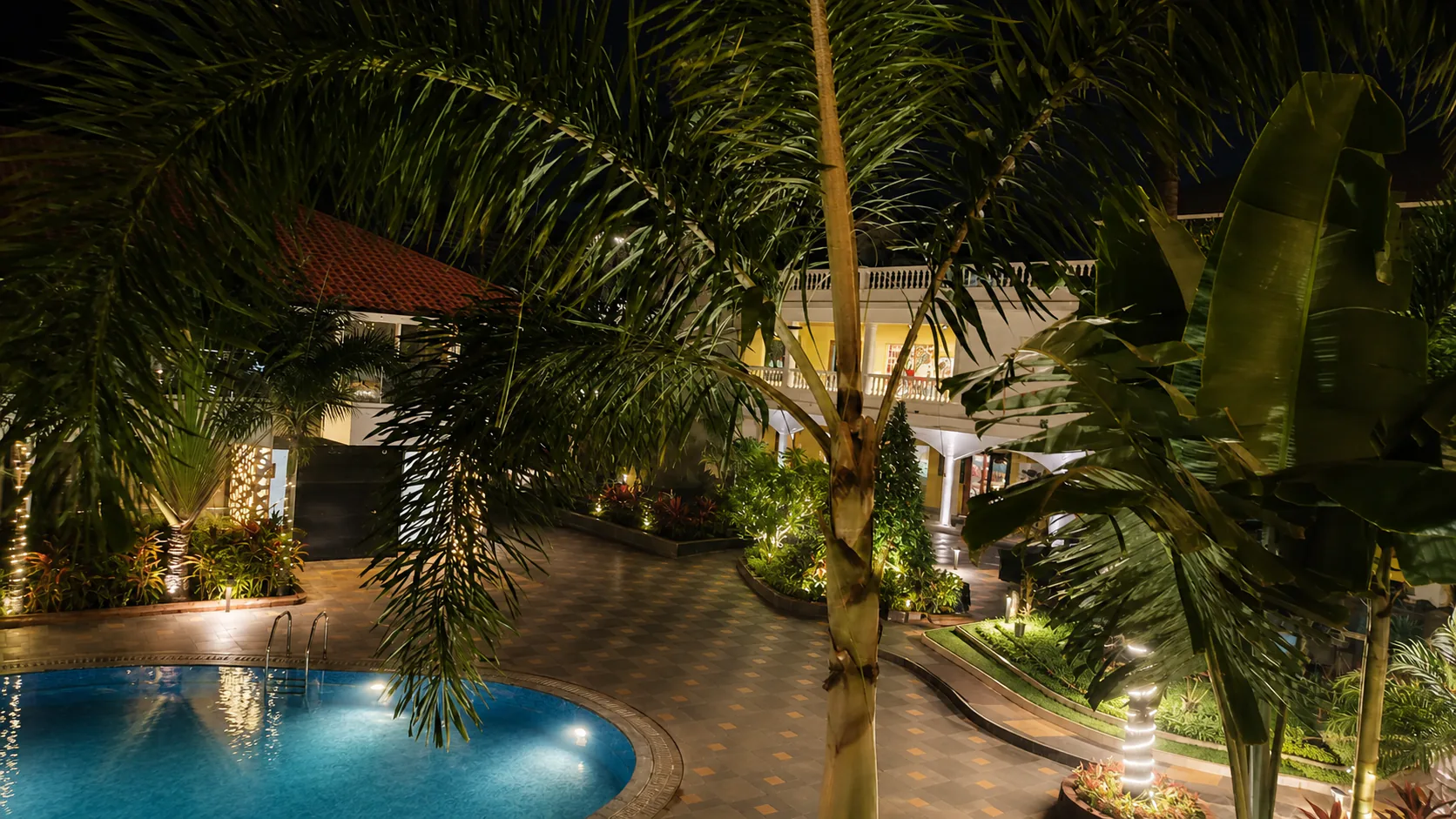Hyatt Place Goa Candolim elevated night pool garden with warm lights, palms and rich reflections