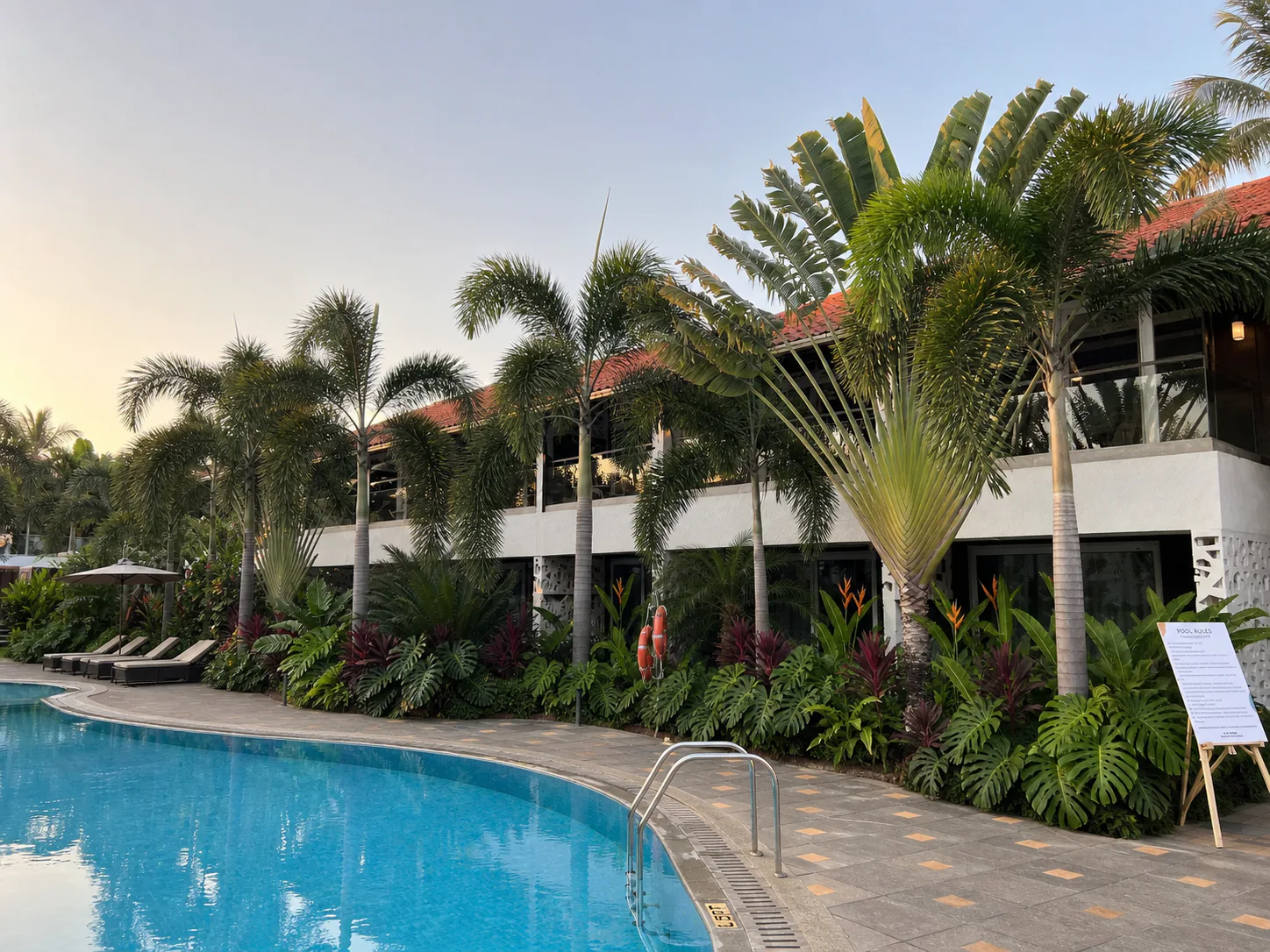Hyatt Place Goa Candolim poolside guest-room wing framed by palms, broad foliage and clean paving