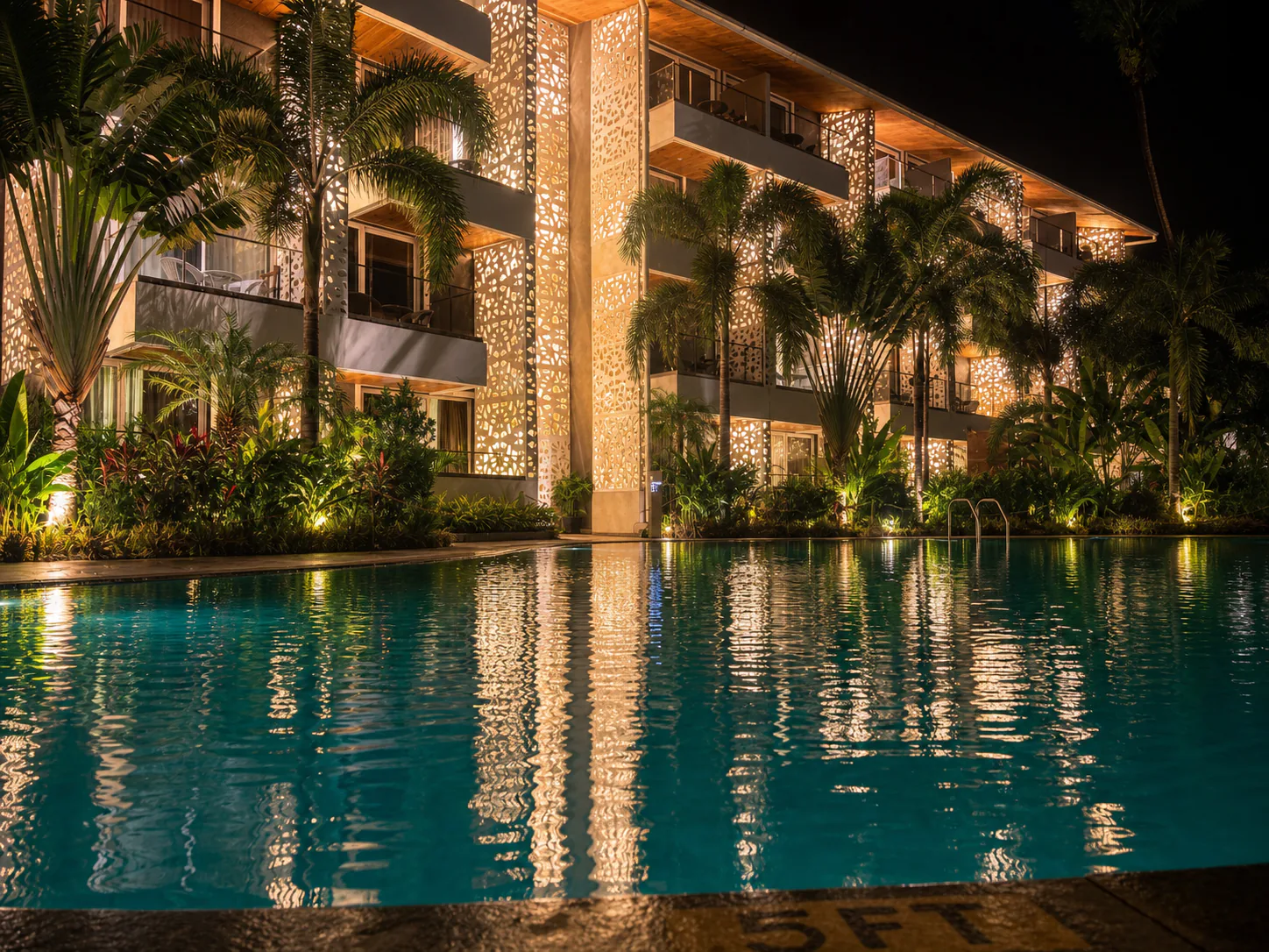 Hyatt Place Goa Candolim low water-level night pool view with luminous jali facade and palm reflections