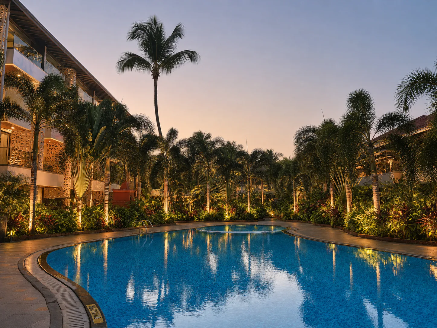Hyatt Place Goa Candolim dusk pool courtyard with clear water, warm lights and lush palms