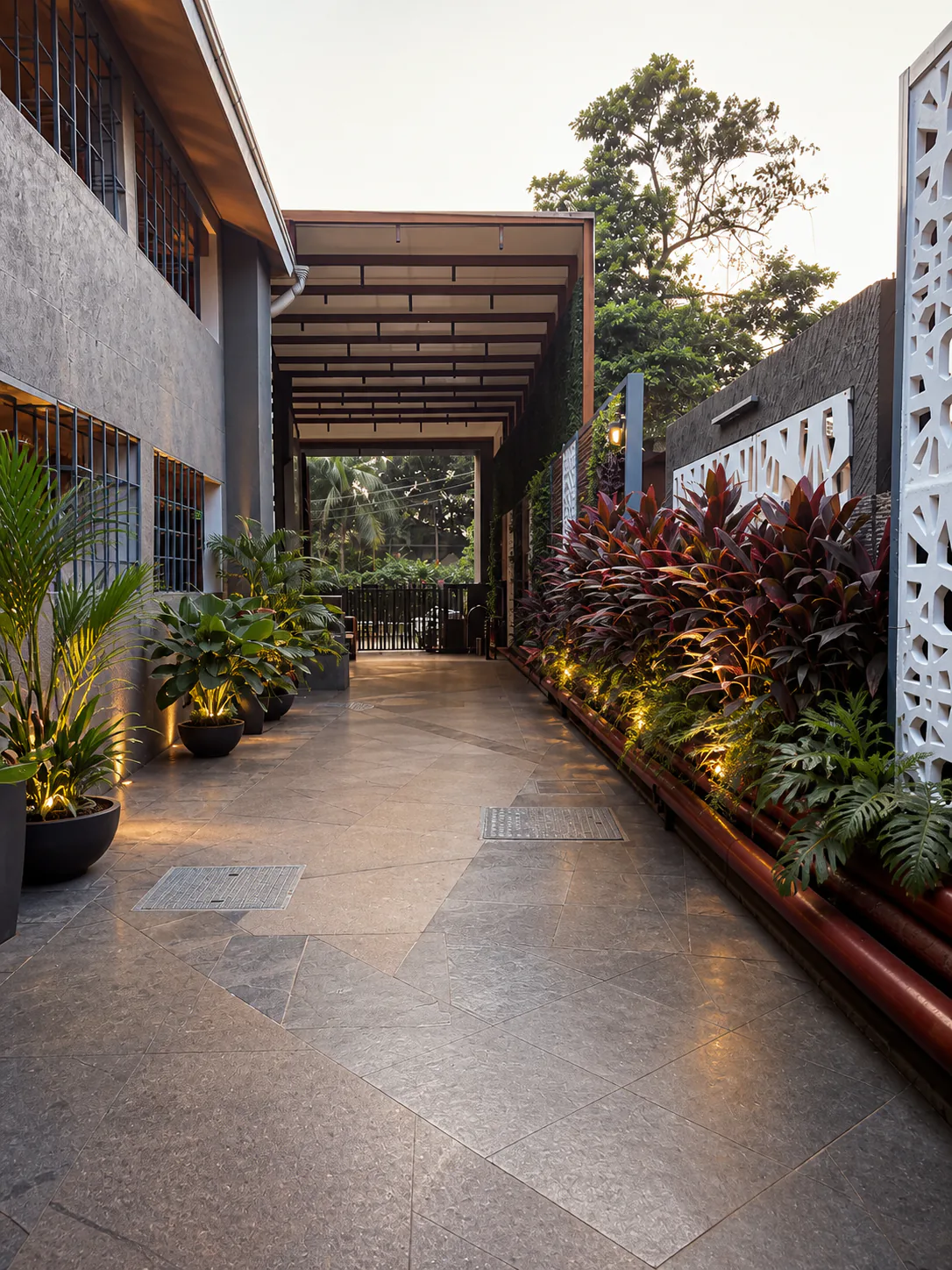 Hyatt Place Goa Candolim covered passage with polished paving, potted palms, cordylines and ferns