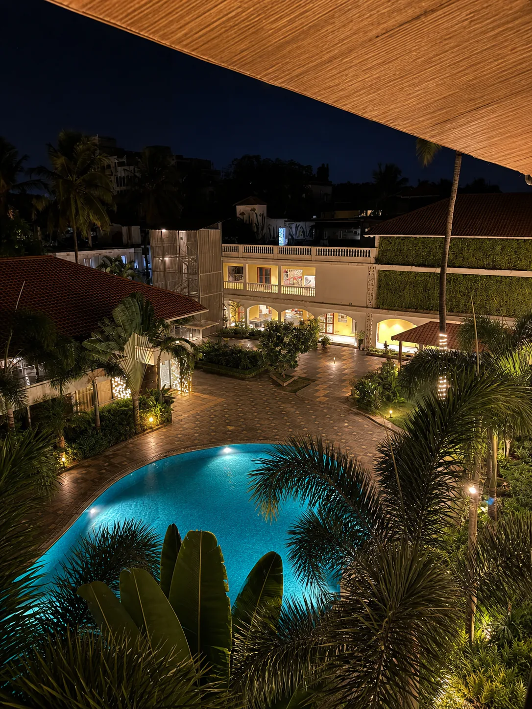 Hyatt Place Goa Candolim elevated night courtyard with luminous pool and warm resort lighting