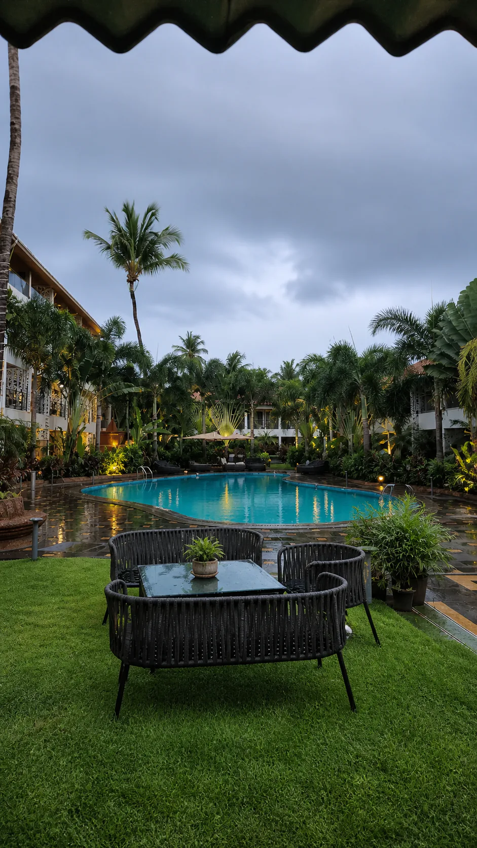 Hyatt Place Goa Candolim post-rain pool lounge with wet reflections, manicured lawn and illuminated palms