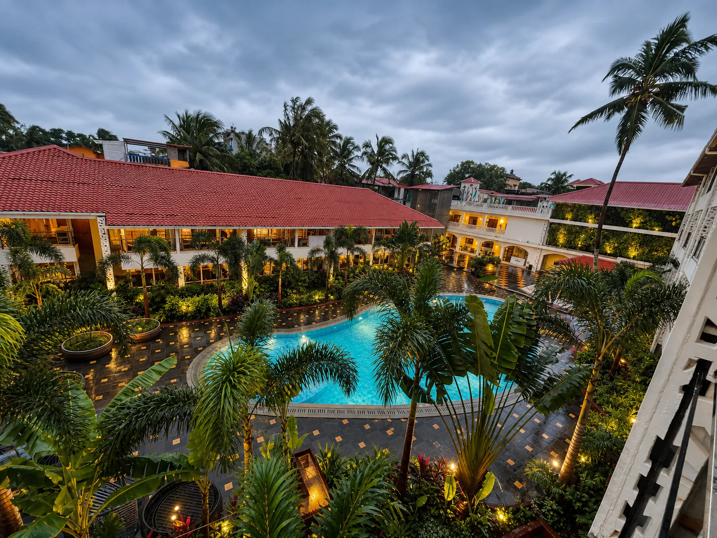 Hyatt Place Goa Candolim elevated monsoon courtyard with wet paving, clear pool and illuminated tropical garden