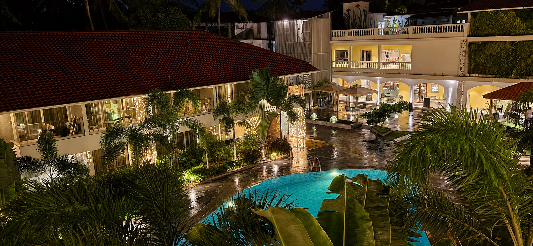 Hyatt Place Goa Candolim elevated nighttime pool courtyard with wet paving and luminous resort landscaping