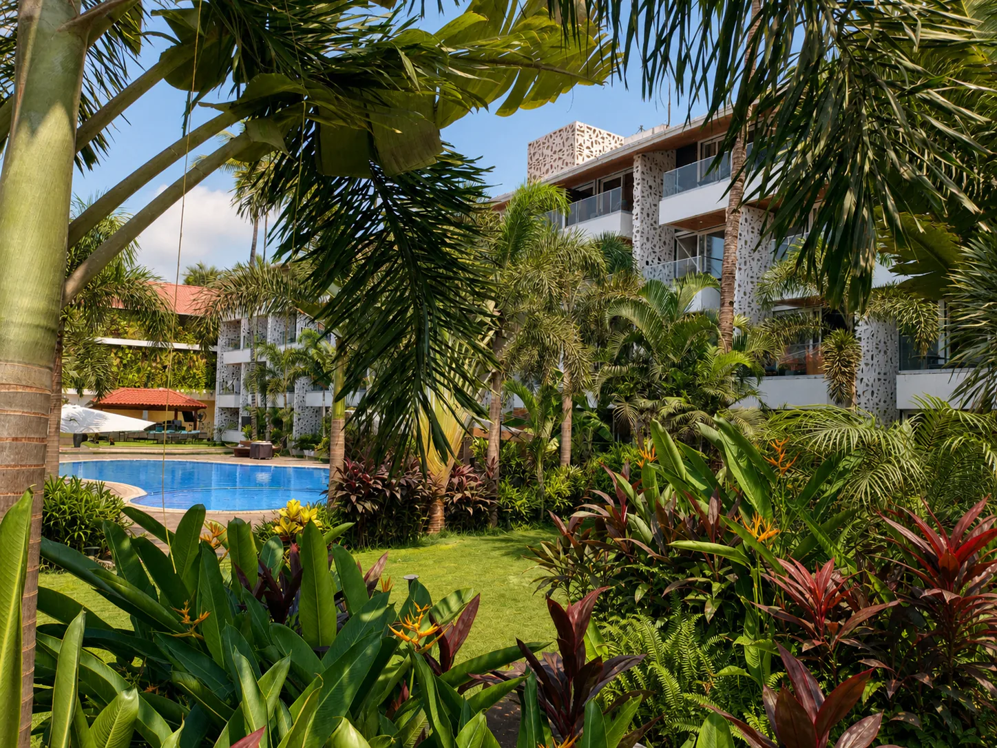 Hyatt Place Goa Candolim lush garden panorama with pool, guest-room wings and flowering tropical foliage