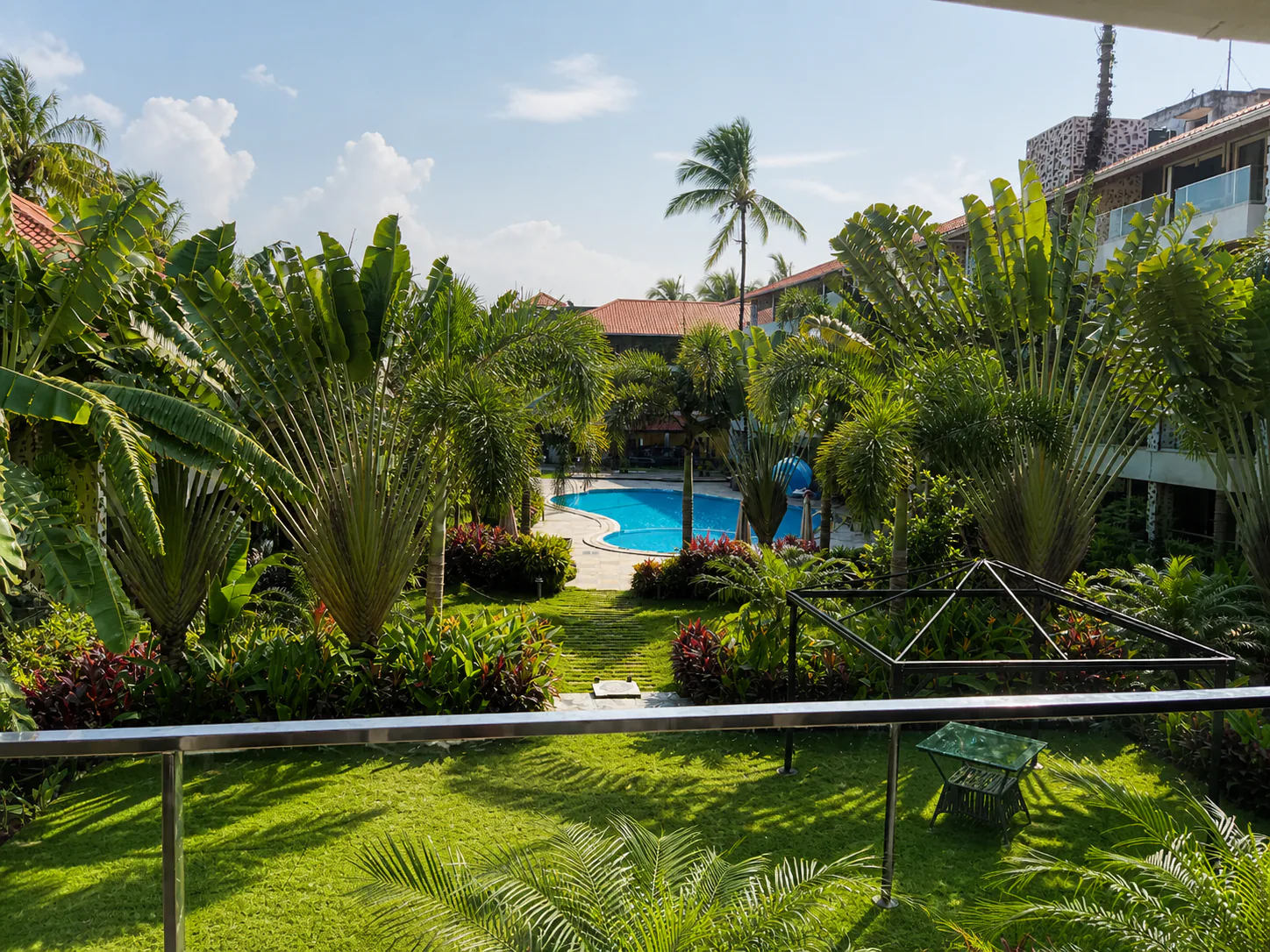 Hyatt Place Goa Candolim terrace view over manicured lawn, traveller palms and clear swimming pool