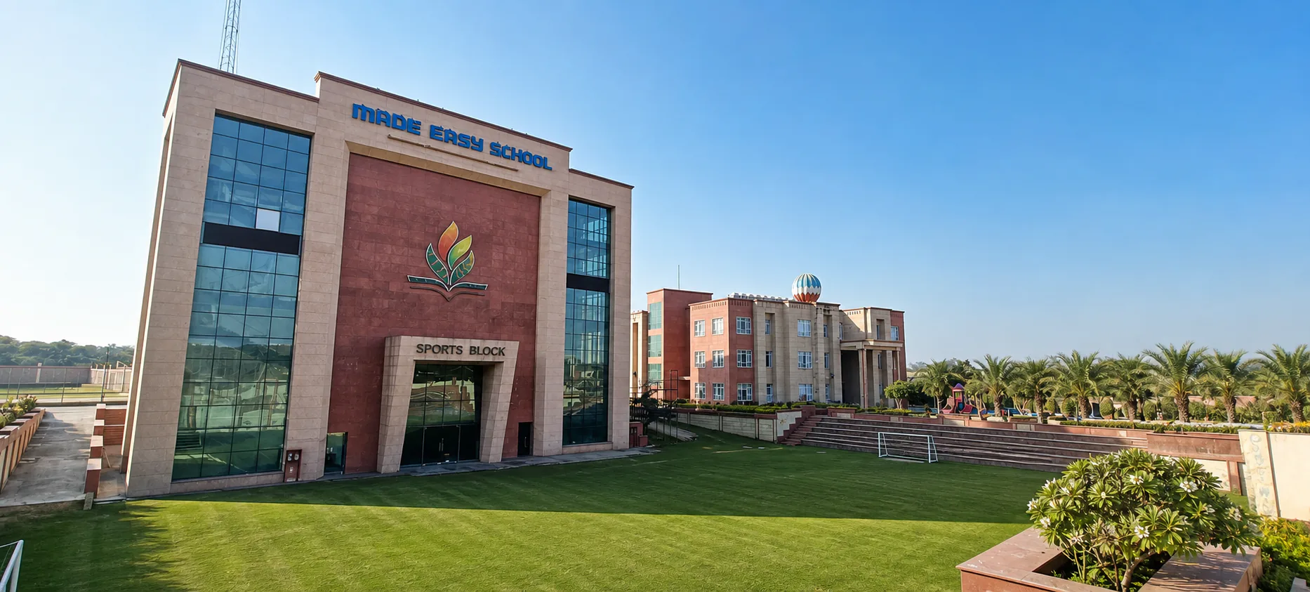 Made Easy School Bhandwari wide Sports Block facade beside a realistic playing lawn and formal boundary planting