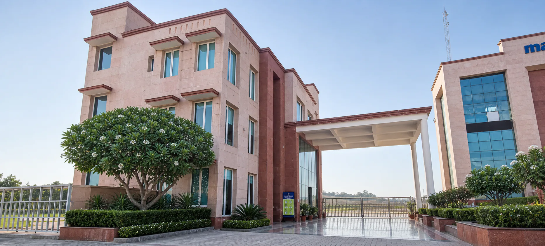 Made Easy School Bhandwari internal connector entrance framed by flowering plumeria, cycads, hedges and polished paving