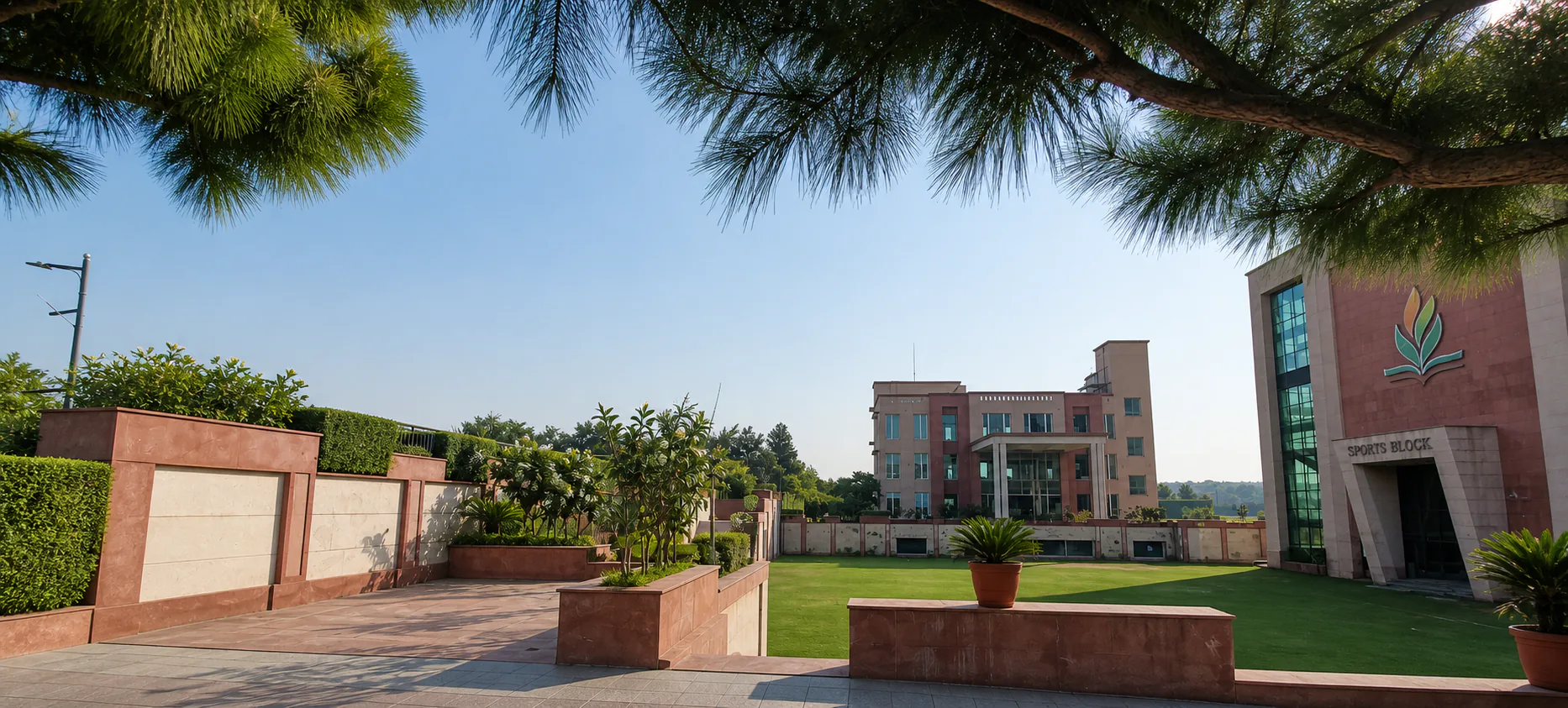 Made Easy School Bhandwari tree-framed courtyard lawn with sandstone walls, formal planters and school buildings beyond