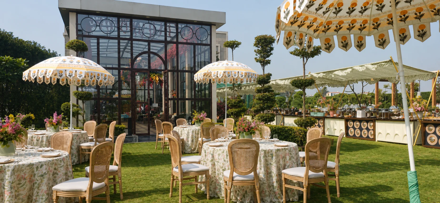 One Farrer event lawn with dining tables, umbrellas, natural turf and coordinated landscape planting around glass pavilions.