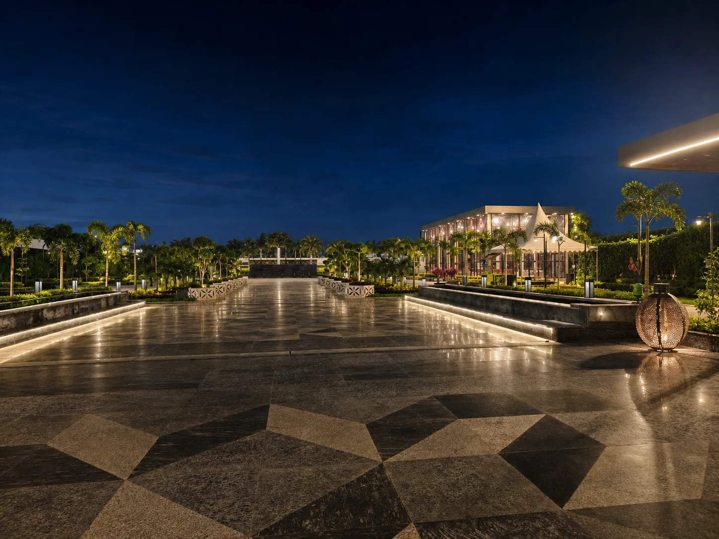 One Farrer arrival court at blue hour with geometric paving, illuminated pavilion, palms and sculptural topiary.