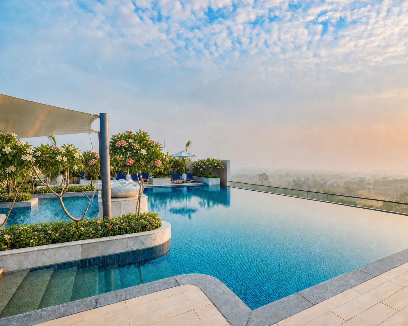 Taj Amer Jaipur rooftop infinity pool with clear blue water and flowering plumeria trees in curved planters.