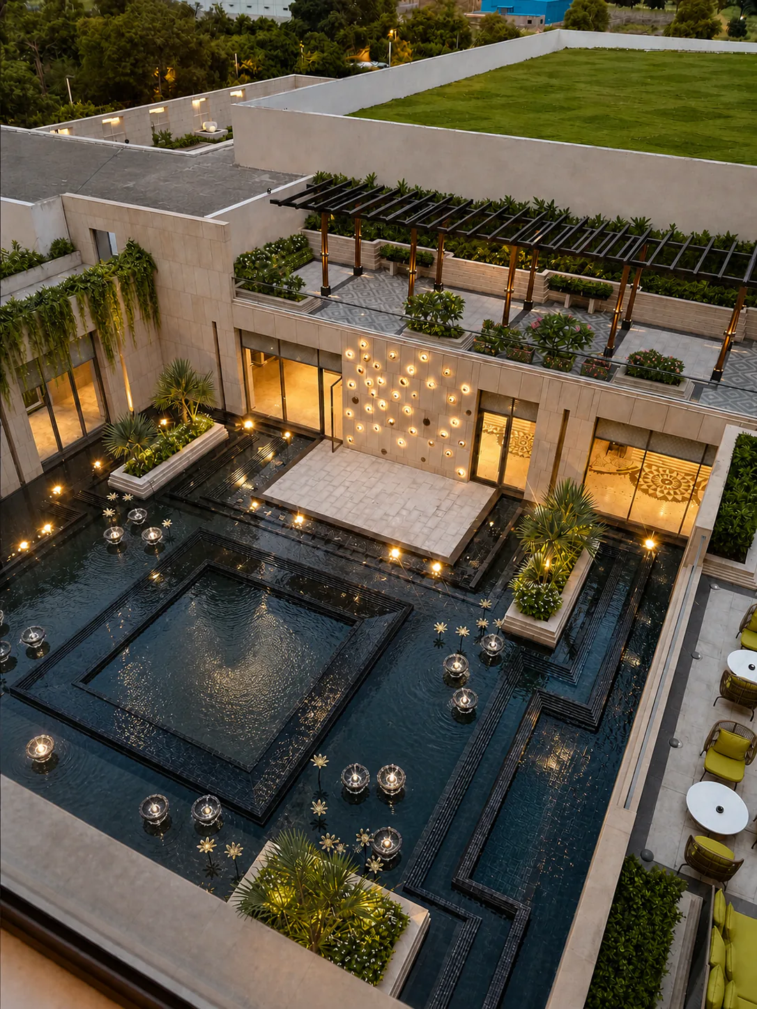Elevated Taj Amer Jaipur courtyard with reflective black water channels, planted palm islands and warm ambient lighting.