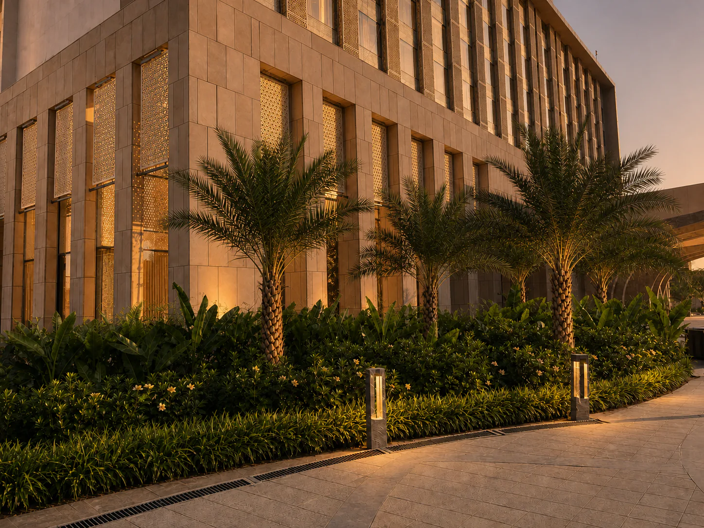 Taj Amer Jaipur facade at golden hour with illuminated screens, warm building lights and date palm planting.