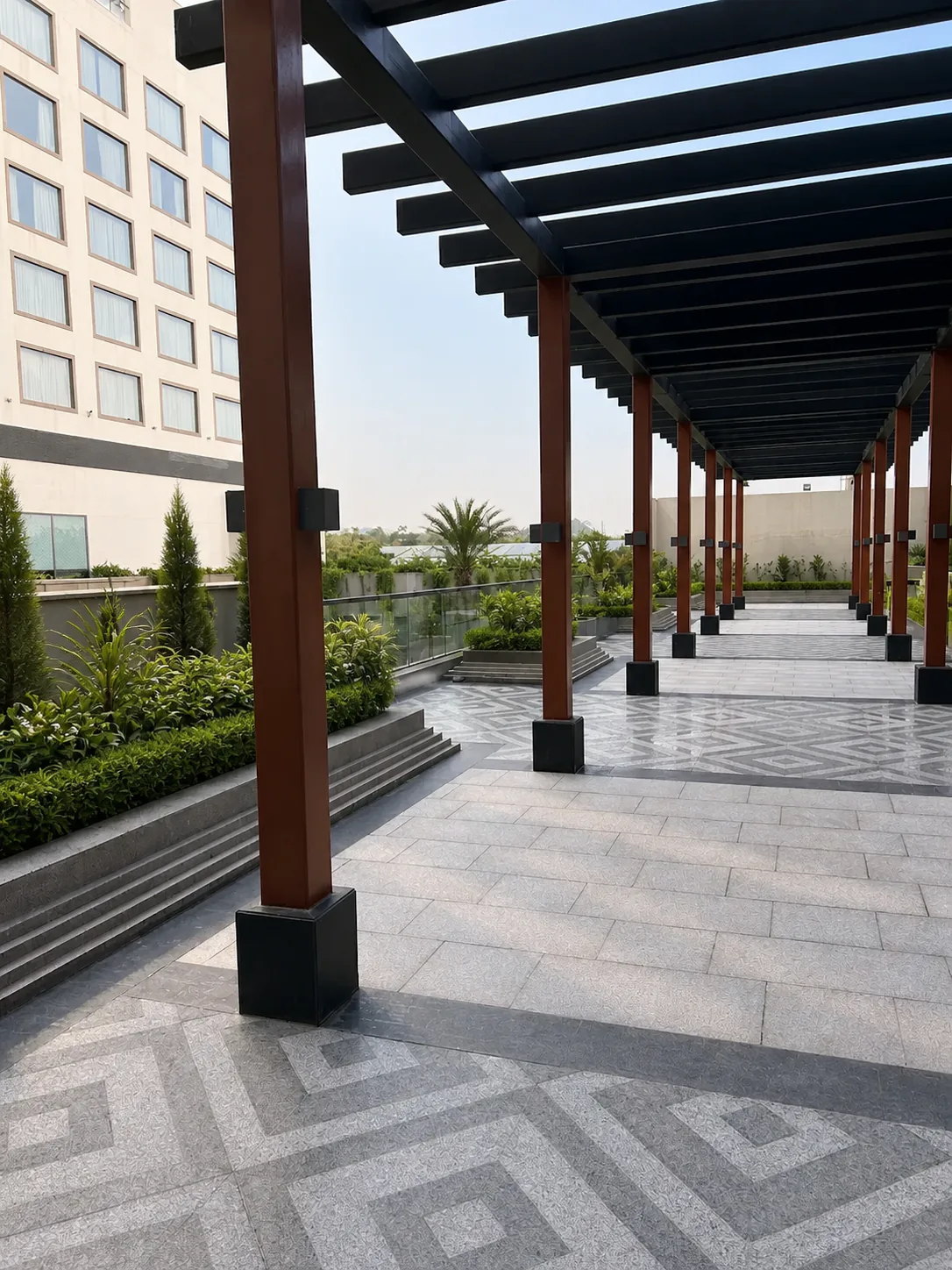Taj Amer Jaipur rooftop pergola walkway with patterned paving and ordered planting in raised terrace beds.
