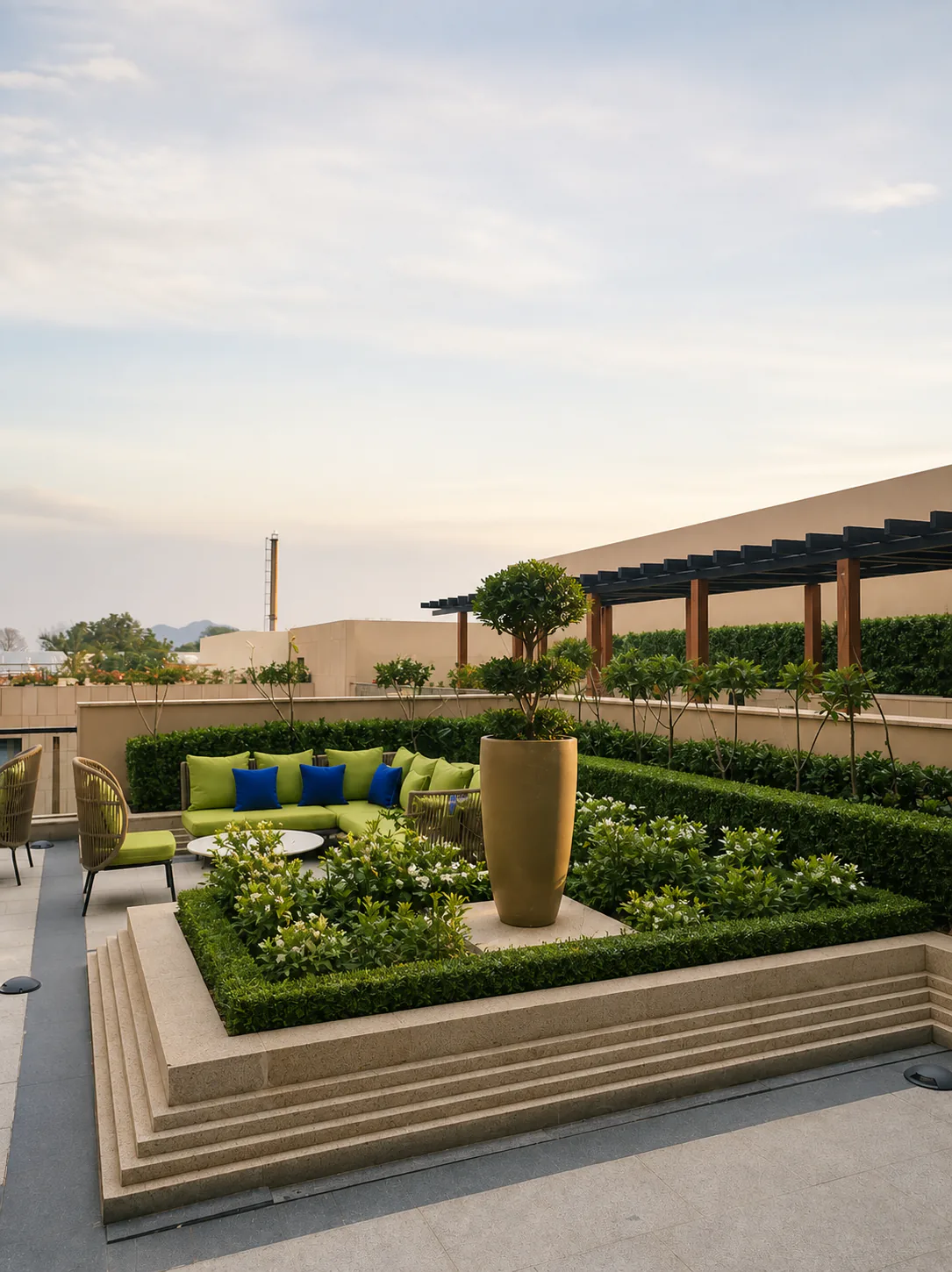 Taj Amer Jaipur rooftop lounge with a stepped geometric garden, sculptural topiary, clipped hedges and green seating.