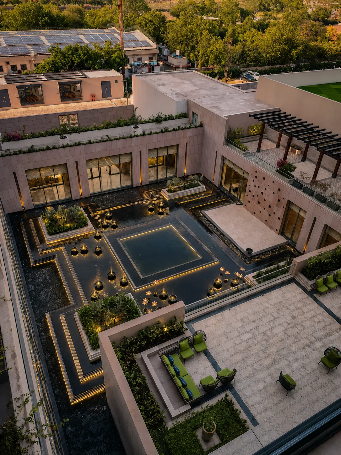 Elevated evening view of the Taj Amer Jaipur courtyard water garden with illuminated channels and lotus bowls.