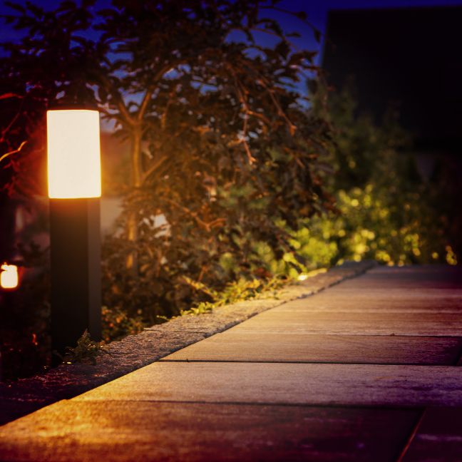 A garden path gently illuminated by sleek, vertical landscape lights, provided by Four Leaf Landscape, offering a harmonious blend of safety and aesthetics for evening strolls.